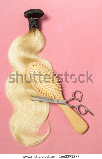 a wooden\
comb and a pair of scissors on wavy black to blonde two tone ombre\
style human hair weaves extensions\
bundles