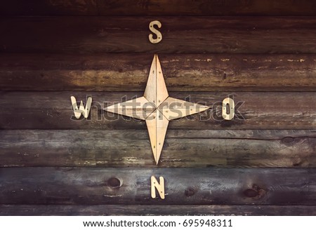 Wooden compass on a wooden wall in a country house. Decorated wall in the form of a compass, indicating the parts of the world North, South, West, East.