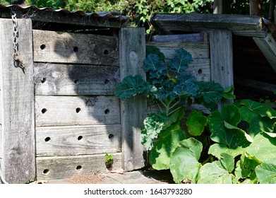 A Wooden Compost Bin With Corrugated Iron Lid And Aeration Holes Drilled In The Side