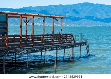 Wooden construction. Pier, platform in the lake. Sunny day. Clear sky. Sun reflection. Water surface.