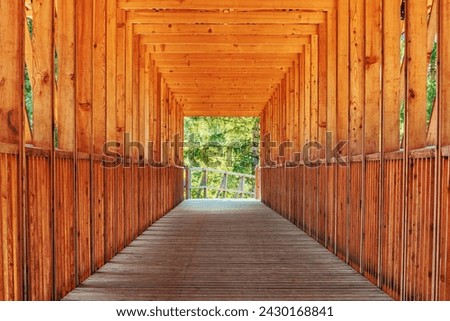 Wooden construction of timber bridge and tunnel with green wooded landscape at the exit, selective focus