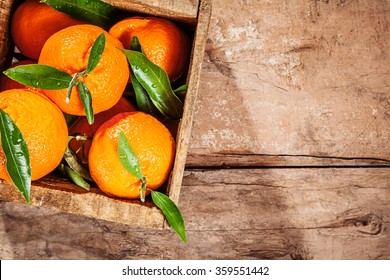 Wooden Crate Of Fresh Colorful Clementines Or Tangerines Displayed At Market, Overhead View On Rustic Wooden Planks With Copy Space