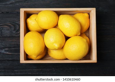 Wooden crate full of fresh lemons on dark background, top view - Powered by Shutterstock