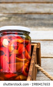 Wooden crate with glass jars with pickled red bell peppers.Preserved food concept, canned vegetables isolated in a rustic composition.