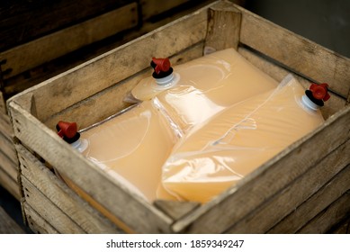 Wooden crates filled with cold press apple juice packed in the bag-in-box system. Production of natural, fresh, organic juice