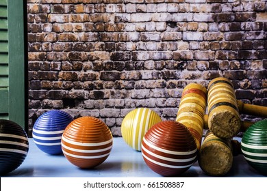 wooden croquet balls and mallets on blue table with green shutter and brick wall background