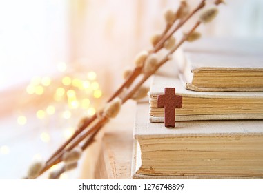 wooden cross, biblical books, fluffy willow twigs on abstract light background. Palm Sunday, Easter holidays. symbol of faith in God, religion. Orthodox, Catholic, Protestant christianity concept