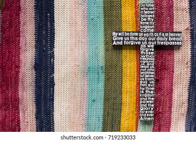 Wooden cross with the Lord's prayer on the  colored striped  carpet background. - Shutterstock ID 719233033