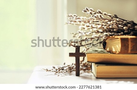 wooden cross, old biblical books and willow twigs close up on table, abstract light background. Orthodox palm Sunday, Easter holiday. Symbol of Christianity, Lent, Faith in God, Church. copy space