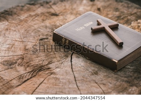A wooden cross on Holy Bible on wooden table. Sunday readings, Bible education. spirituality and religion concept.