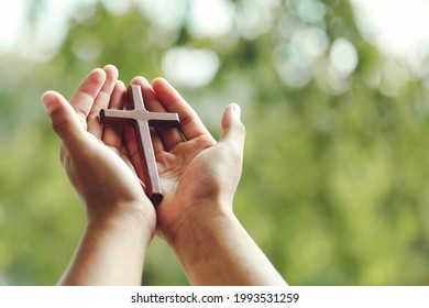 Wooden cross on praying hands with outdoor background. international prayer day.Easter and Good friday concept. - Shutterstock ID 1993531259