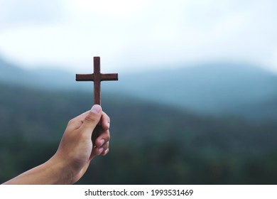 Wooden Cross On Praying Hands With Outdoor Background. International Prayer Day.Easter And Good Friday Concept.
