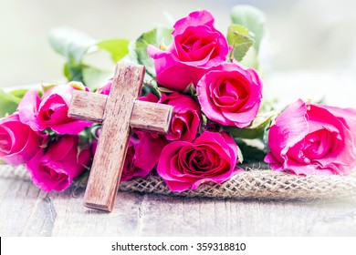 The wooden  cross and pink roses on wooden  background, burred background, concept, Valentine background