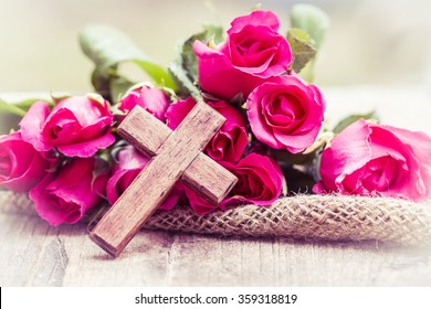 The wooden cross and pink roses on wooden  background, burred background