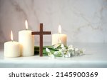 Wooden cross, snowdrops flowers and candles on table, abstract background. Religious church holiday. symbol of faith in God, Christianity Feast, Easter, Palm Sunday, Lent