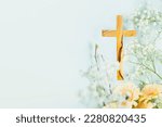 Wooden cross with spring flowers on blue background with copy space. Religion background. Religious church holidays. Christianity Feast, Easter, Palm Sunday, Christening, church wedding. Flat lay