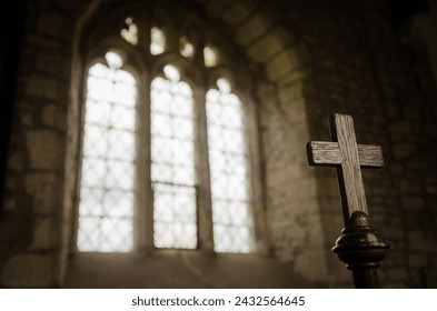 Wooden cross, symbol of Christian faith, inside a sacred church in front of a beautiful antique stained glass window. Warm light. Easter holy week Good Friday concept. - Powered by Shutterstock