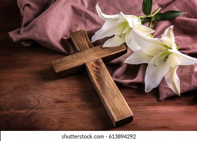 Wooden cross and white lily on table
