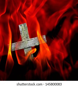 Wooden crucifix in hot inferno with yellow and red flames