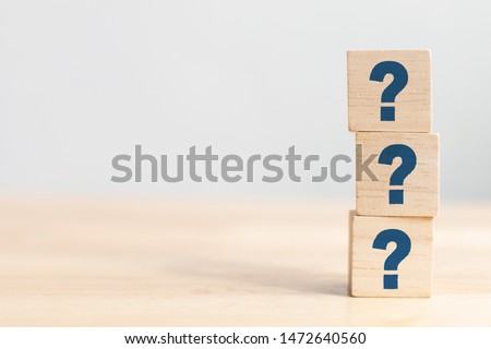 Wooden cube block shape with sign question mark symbol on wood table