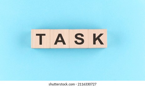 Wooden cube block with text TASK on blue background