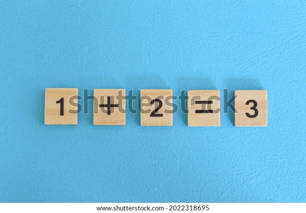 Wooden cube blocks with one plus two equal three.\
Math concept
