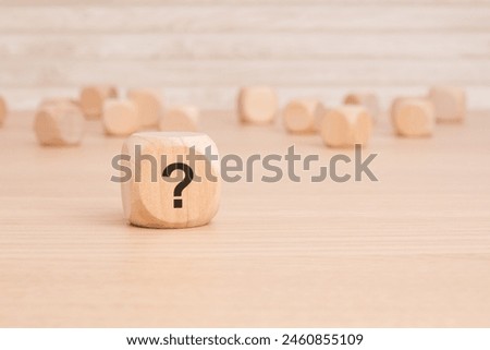 a wooden cube, featuring a question mark symbol written on one side