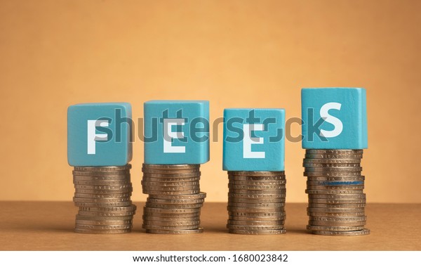 Wooden cube\
with Fees words on stacked of coins.\
