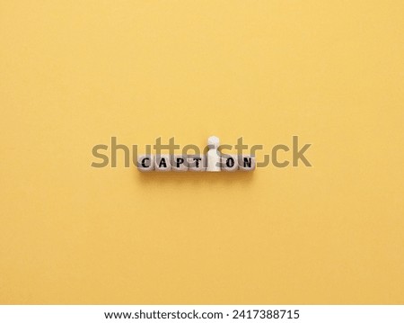 Wooden cube and figure with CAPTION  text. Concept of sentence usage, structure of something over yellow background