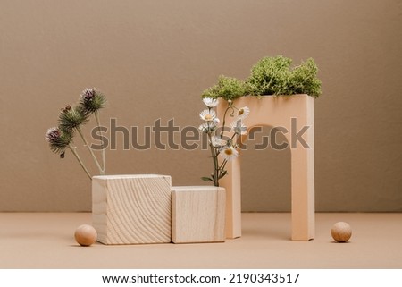 Wooden cube podium with plants for product and cosmetic presentation. Geometric podium with moss, camel thorn and chamomile, brown tones
