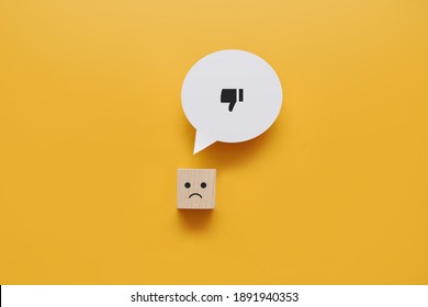 A Wooden Cube With A Sad Face And A Dislike Icon Above It. Negative Ratings, Lack Of Confidence And Sadness In A Person's Life