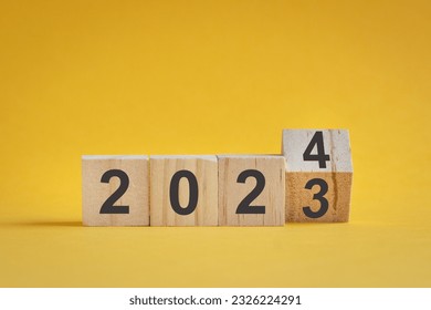 Wooden cube stock flipping, change from 2022 to 2023. Yellow color background, with copy space.