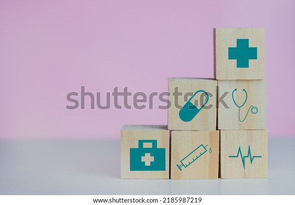 Wooden cubes block with\
insurance health car medical symbol on the pink background and copy\
space.