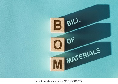 Wooden Cubes Building The Word BOM Bill Of Materials On Blue Background.