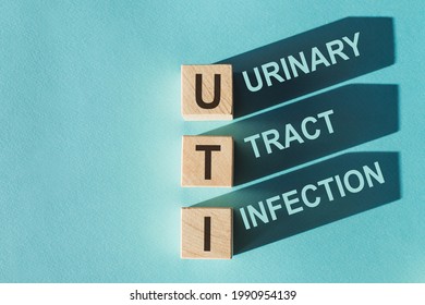 Wooden cubes building word UTI - (abbreviation Urinary Tract Infection) on light blue background.