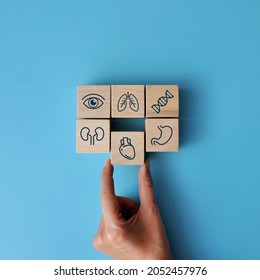 Wooden cubes with the image of medical icons: heart, dna, eye, stomach, kidneys, lungs. A man heals the heart - Powered by Shutterstock