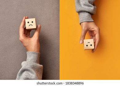 Wooden cubes with the image of a sad and cheerful face. Choosing positive or negative thinking in life