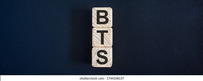 Wooden cubes with the inscription 'BTS'. Beautiful dark background, copy space.