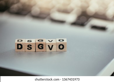 Wooden cubes with the letters “DGSVO” for Datenschutzgrundverordnung are lying on a laptop