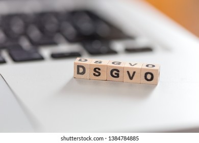 Wooden cubes with the letters “DGSVO” for Datenschutzgrundverordnung are lying on a laptop