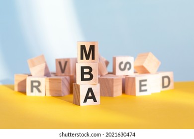 Wooden Cubes With Letters MBA Arranged In A Vertical Pyramid, Grey And Yellow Background, Business Concept. MBA - Short For Master Of Business Administration