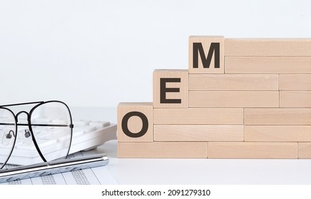 wooden cubes with letters OEM on white table with keyboard and glasses