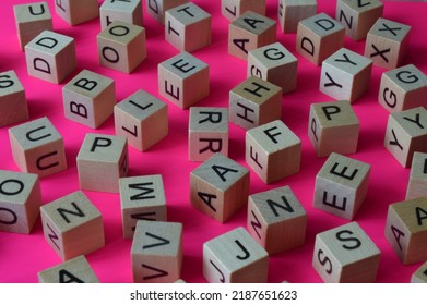 Wooden cubes with letters scattered randomly on a pink background