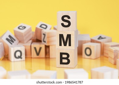 Wooden Cubes With Letters Smb Arranged In A Vertical Pyramid, Yellow Background, Reflection From The Surface Of The Table, Business Concept. Smb - Short For Server Message Block