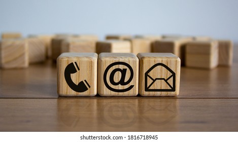 Wooden cubes with mail and phone marks, contact and information icons. Beautiful wooden table, white background. Business concept. Copy space.