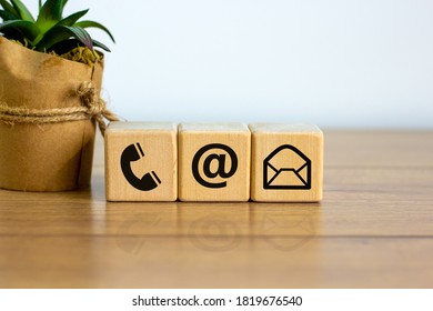 Wooden cubes with mail and phone marks, contact and information icons. Beautiful wooden table, white background. Business concept. Copy space.