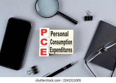 wooden cubes PCE- personal consumption expenditure wtih notebook , magnifier and smartphone, business - Shutterstock ID 2241511005
