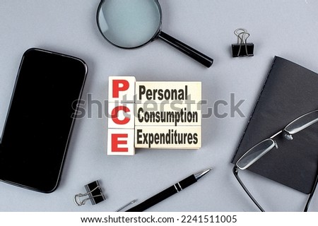 wooden cubes PCE- personal consumption expenditure wtih notebook , magnifier and smartphone, business