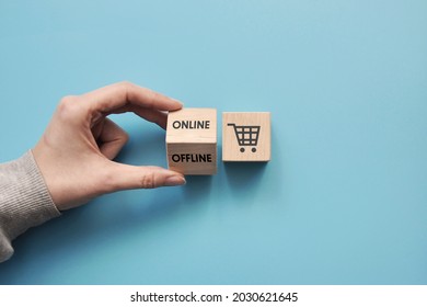 Wooden cubes with a picture of shopping baskets and the inscription: online and offline. Symbol for online or offline purchases