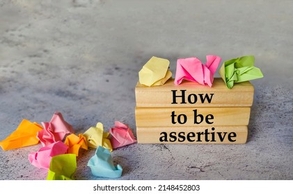 Wooden cubes with sign How to be Assertive and crumpled paper balls  - Shutterstock ID 2148452803